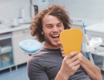 Dental patient looking at smile in mirror after preventive dentistry