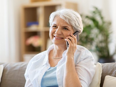 An older, smiling woman talking on a cell phone
