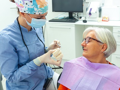A dentist showing model dentures to an older woman