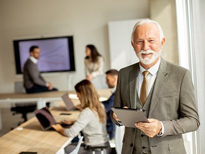 A senior businessman working on a digital tablet in an office setting