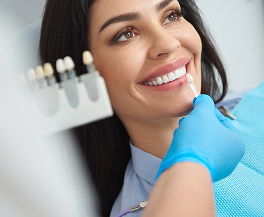 A dentist assessing the shade of a woman’s smile