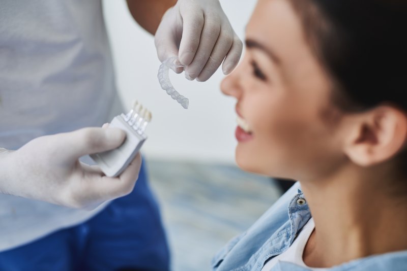 A dentist showing clear aligner trays to a young woman